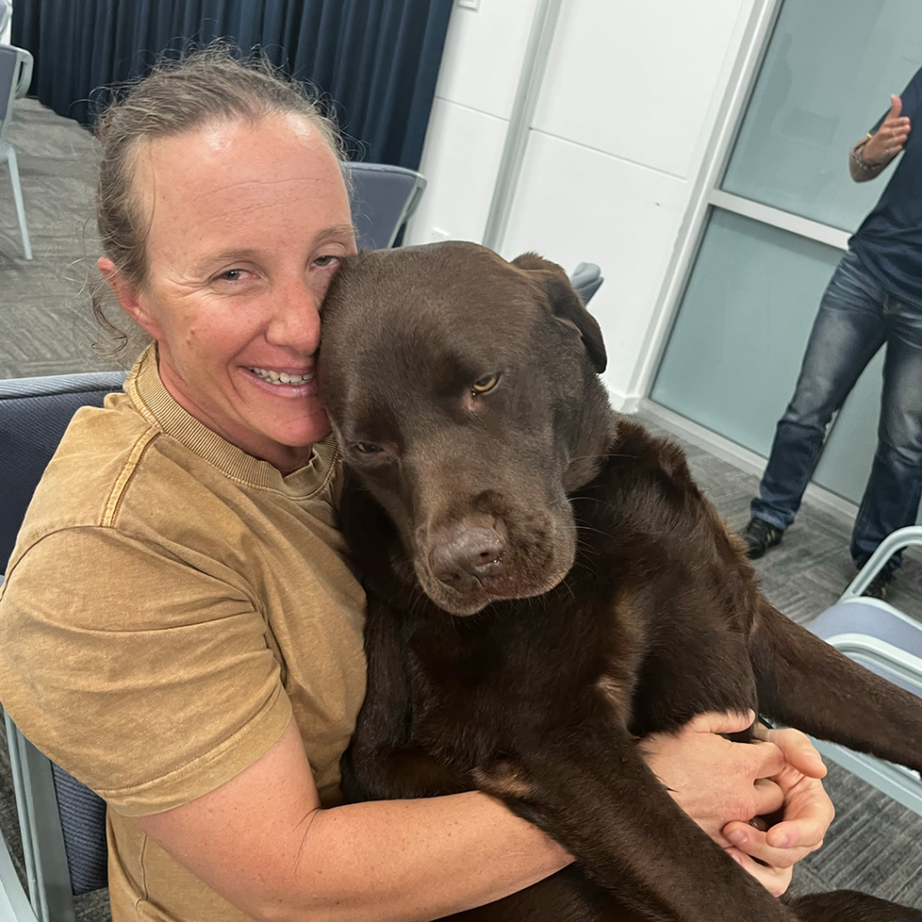 Invictus Games alumni Taryn cuddles up to her brown-haired service dog Gigi